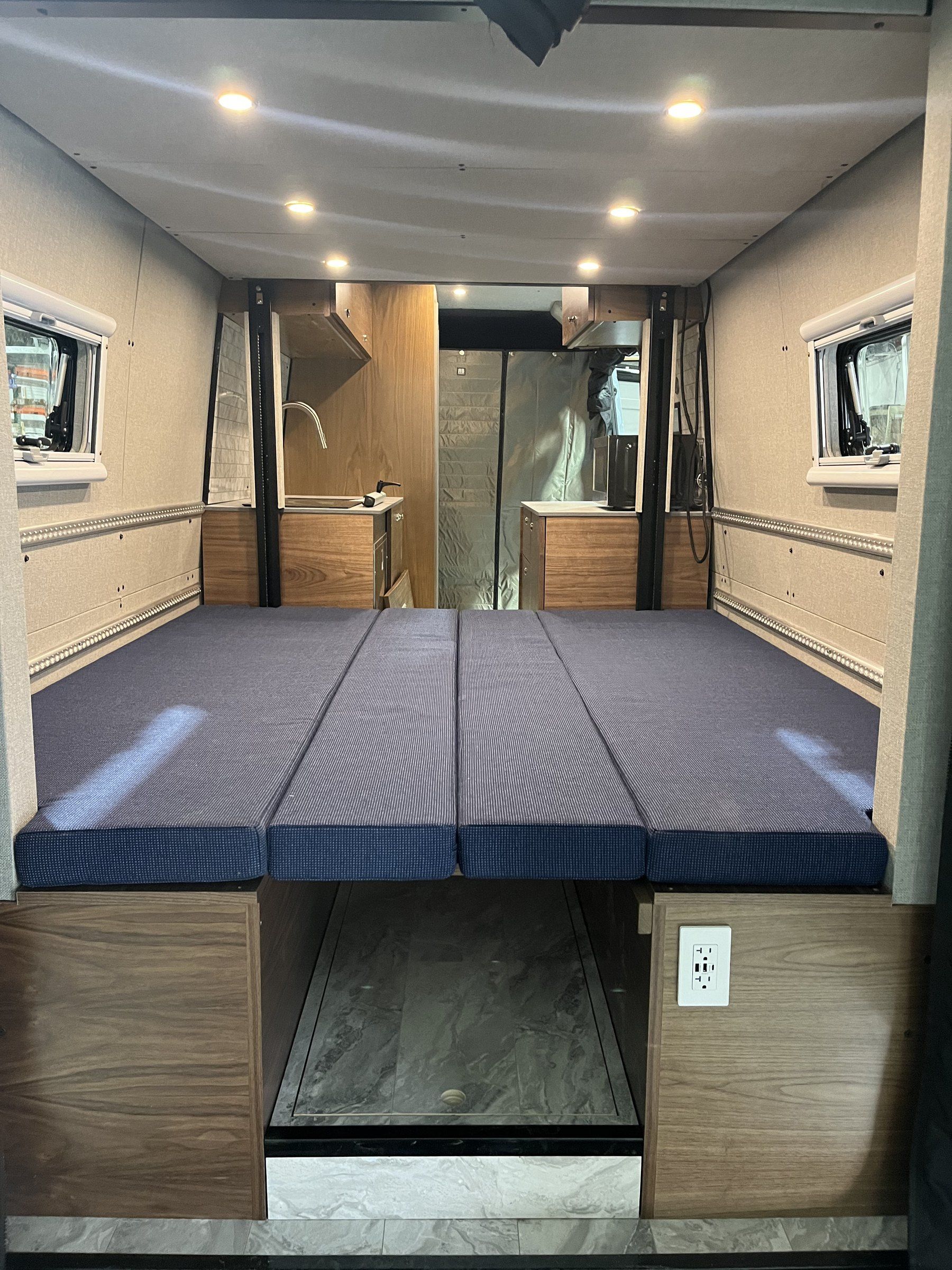Rear with the dinette made up as a bed, cabinets on both sides.