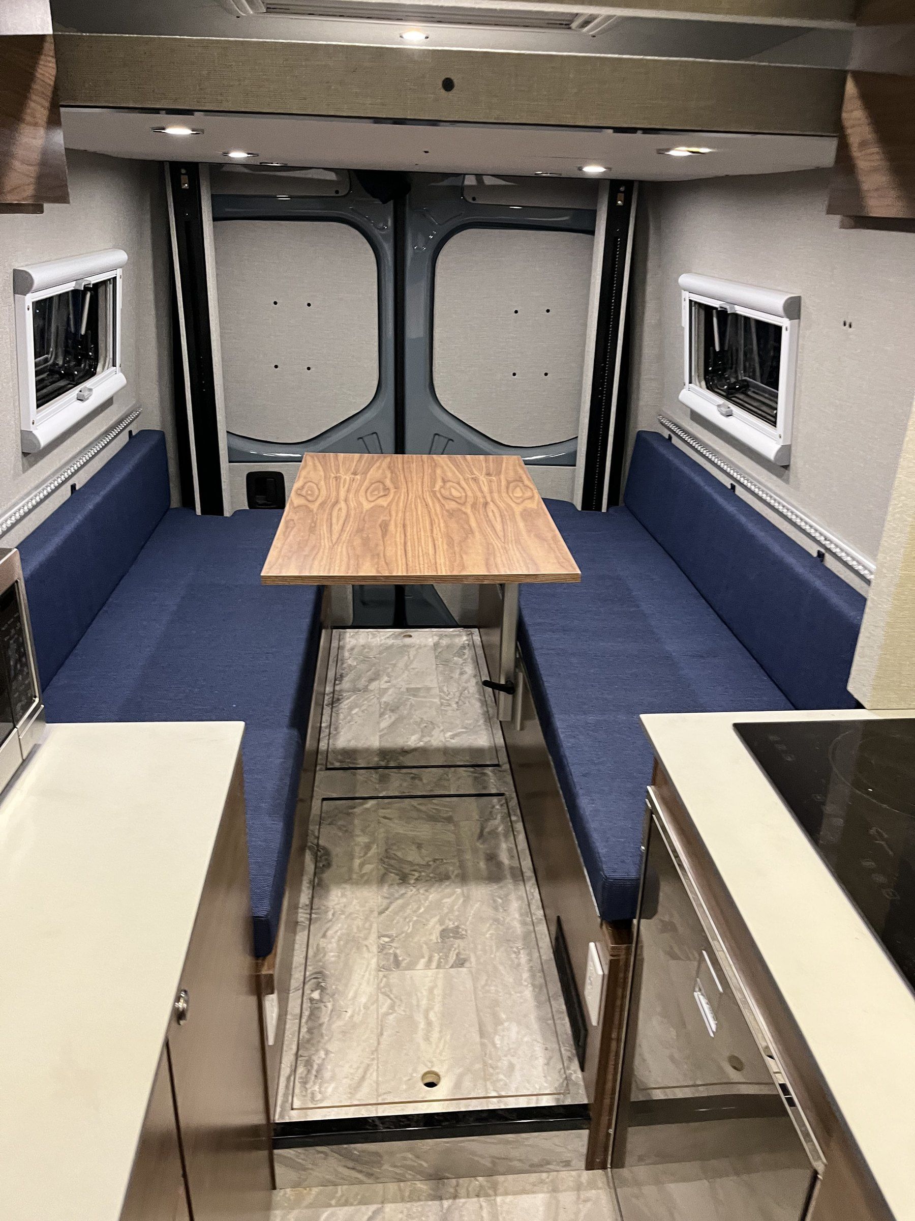 Rear dinette with navy upholstered benches and a walnut table.