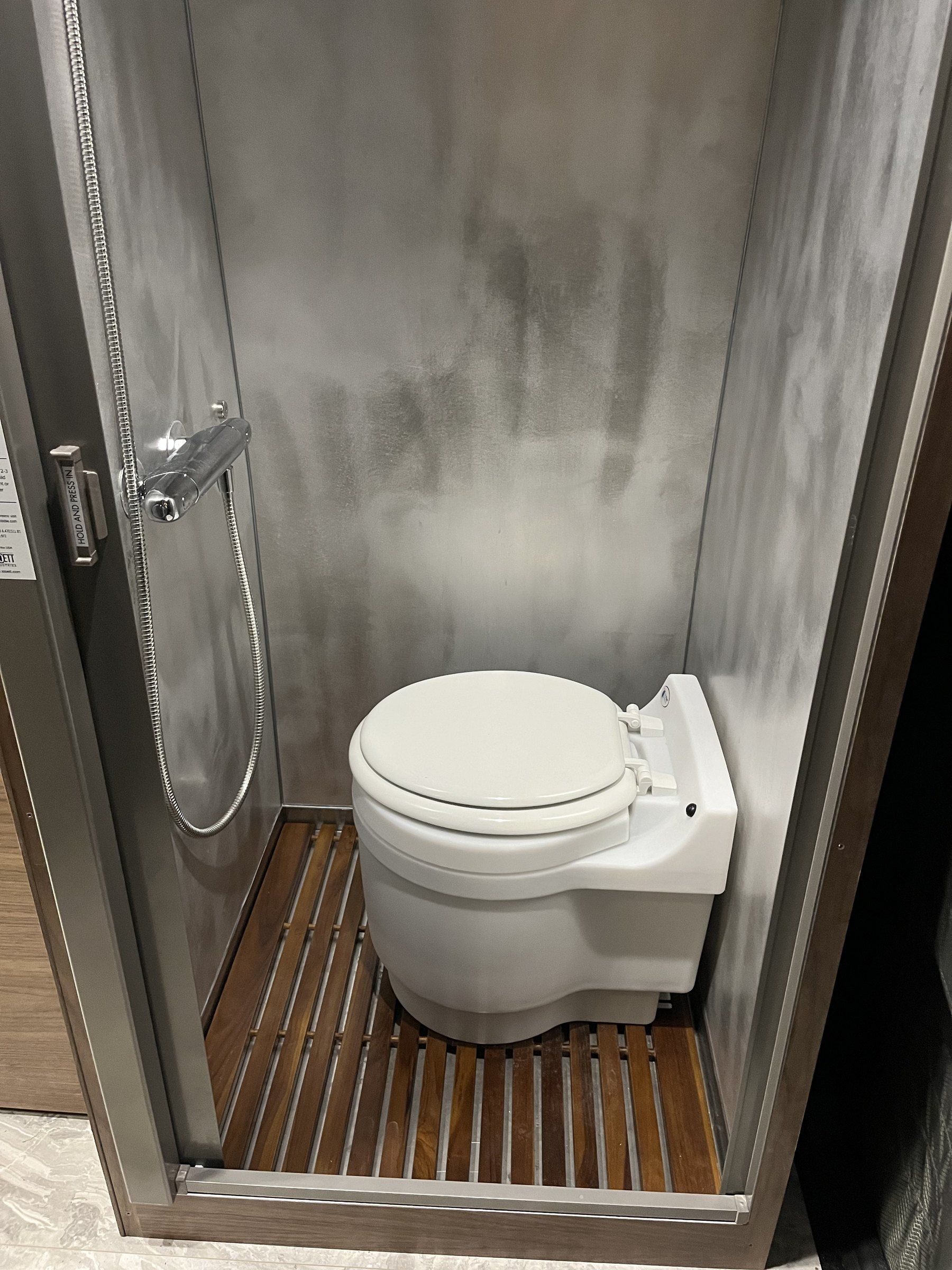 Aluminum shower with teak floor, Moen head and dry flush toilet.