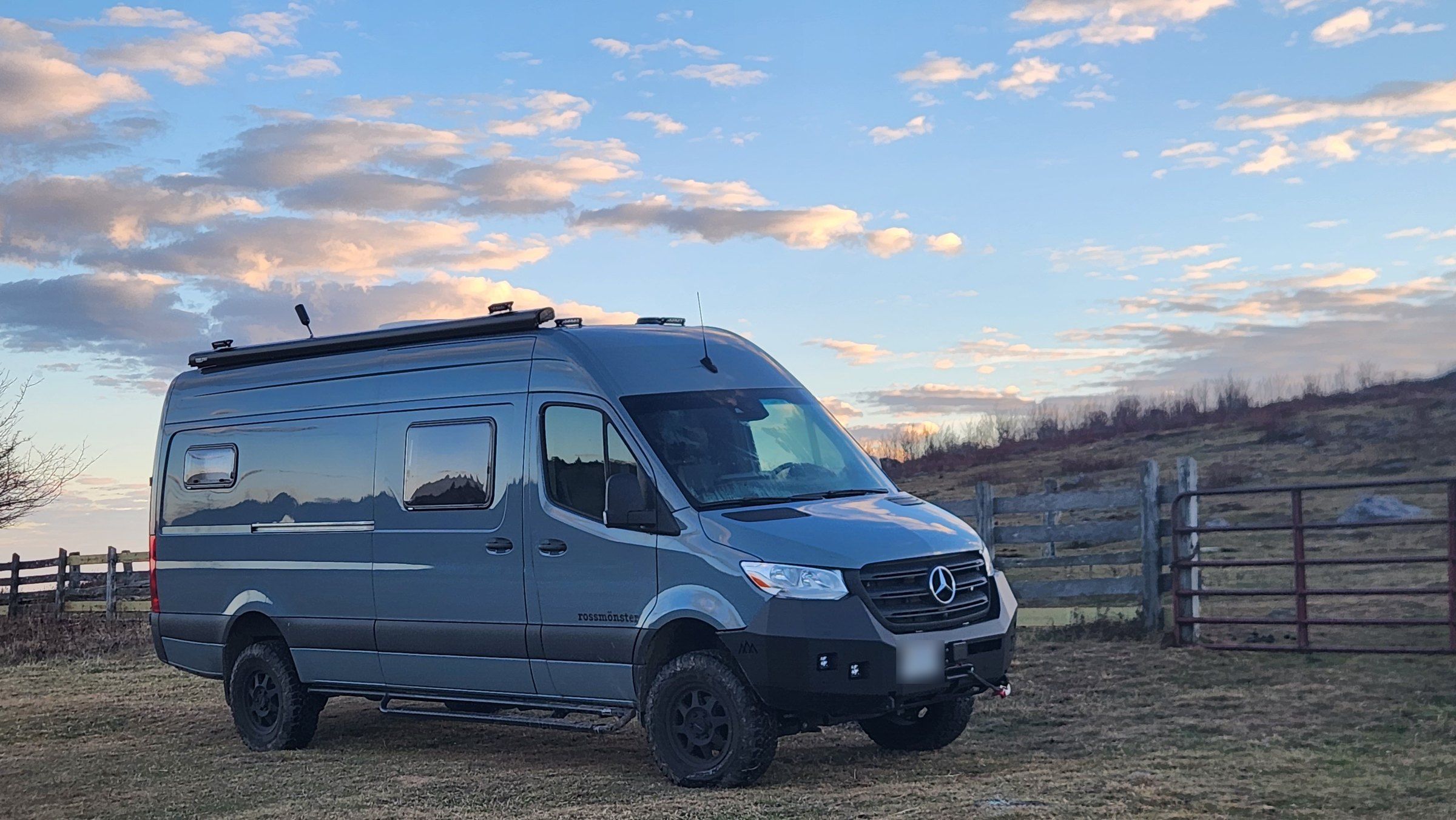 The van at golden hour in a Blue Ridge pasture, wooden fence behind.